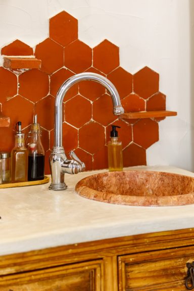 Évier en pierre et détails de cuisine – Appartement Tahaa Évier en marbre avec robinet en métal et fond en carreaux hexagonaux rouges.