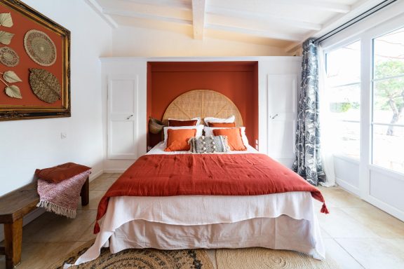 Chambre lumineuse avec lit à baldaquin et murs orange, décorée avec des œuvres d'art.