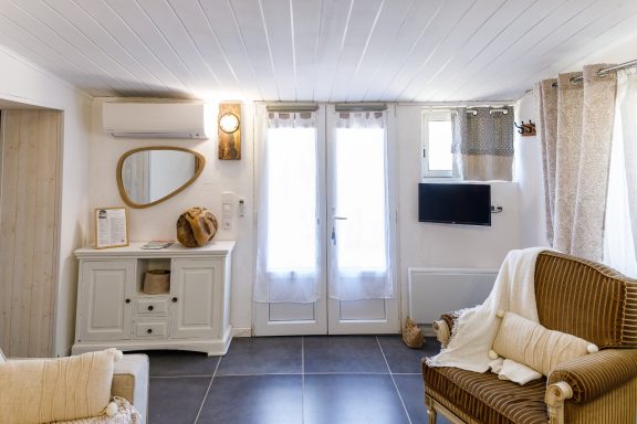 Entrée appartement Tahaa, Chambre d'hôtes, Cotignac, Var Intérieur lumineux avec un meuble blanc, un miroir et des fenêtres. Tapis et sièges confortables.