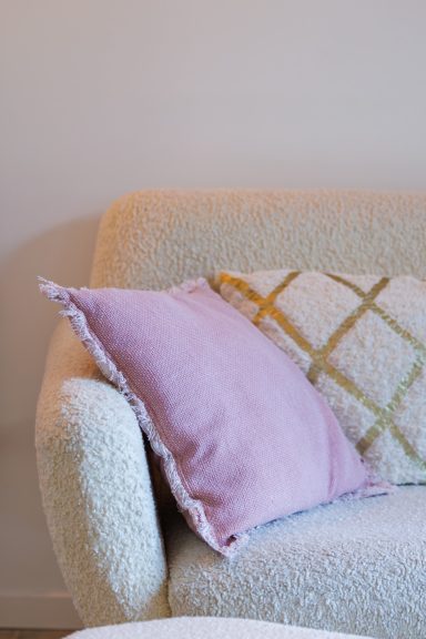 Canapé avec coussins rose et crème, décor minimaliste et moderne.
