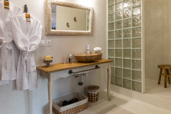 Salle de bain moderne avec lavabo en bois, miroir et peignoirs suspendus.