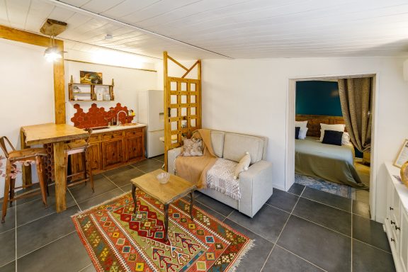 Espace de vie chaleureux – Appartement Tahaa Intérieur d'un salon avec un canapé, une table à manger et un lit en arrière-plan.