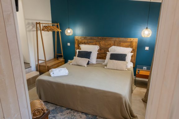 Chambre moderne avec lit double, murs bleu foncé et décoration minimaliste.