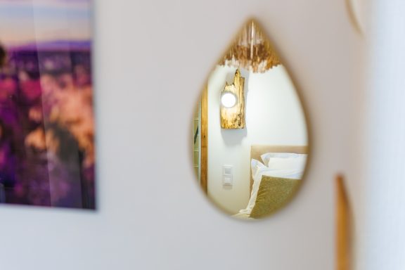 Miroir en forme de goutte avec un décor intérieur flou en arrière-plan.