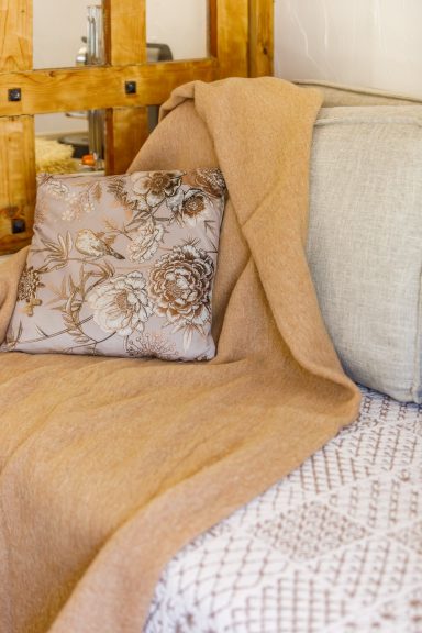 Détails textiles raffinés d’une chambre à la Bastide Tahaa Coussins décoratifs sur un lit avec une couverture beige drapée.