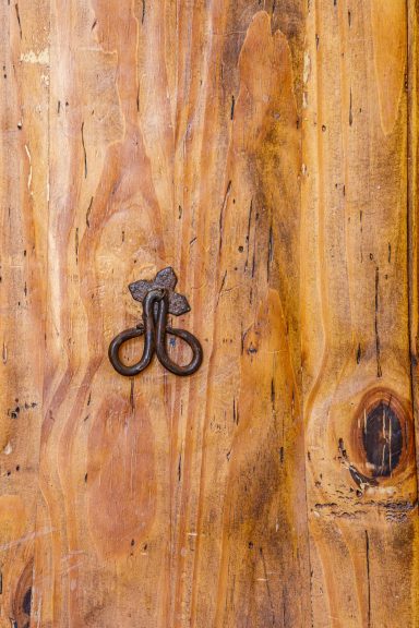 Détail authentique d’une porte en bois à la Bastide Boulon en métal sur une surface en bois, texture naturelle.
