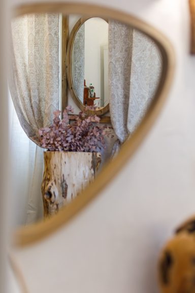 Détail décoratif et miroir – Suite Mooréa - chambre d'hôtes - Var Vase en bois avec des fleurs séchées, reflet dans un miroir et rideaux en arrière-plan.