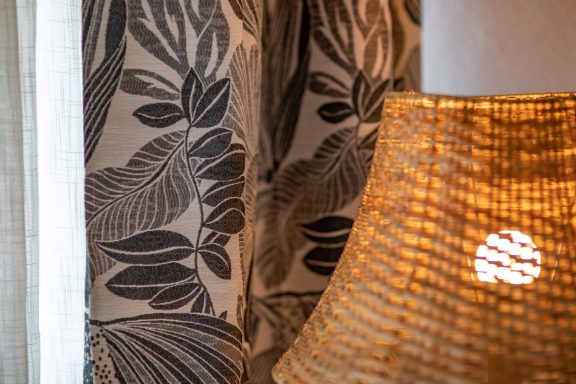 Tissu à motifs de feuilles avec un lampadaire en osier éclairé.