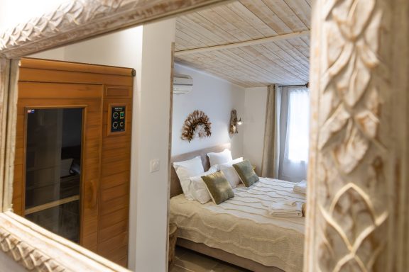 Chambre à coucher avec lit double, décorée et miroir orné, vue sur un sauna.